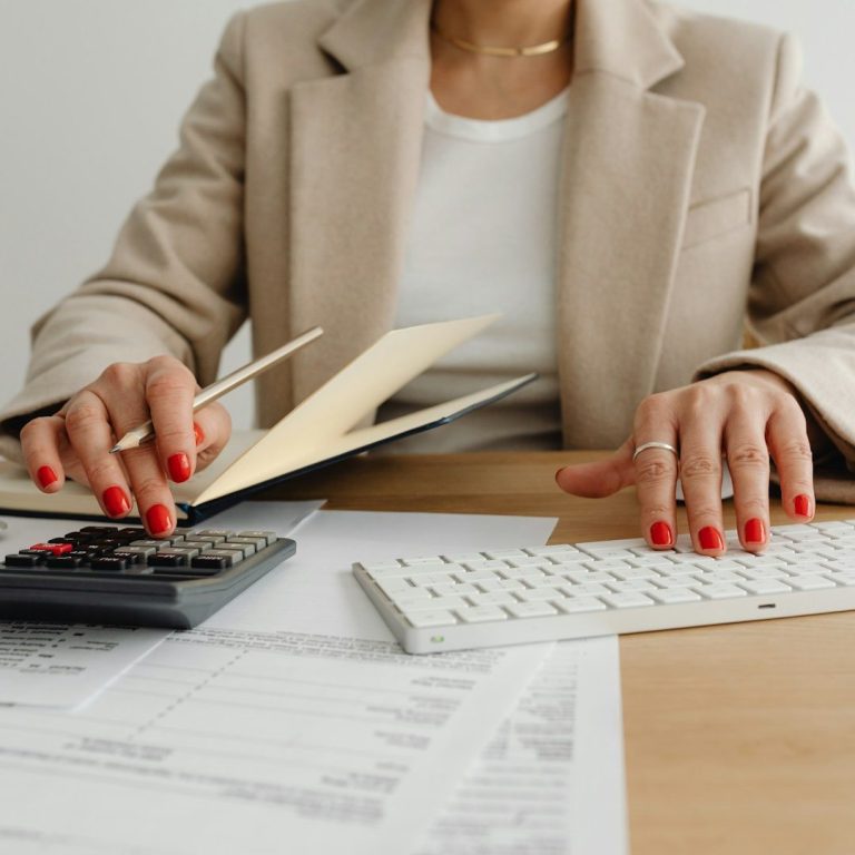 A person using a calculator and holding documents on a desk.